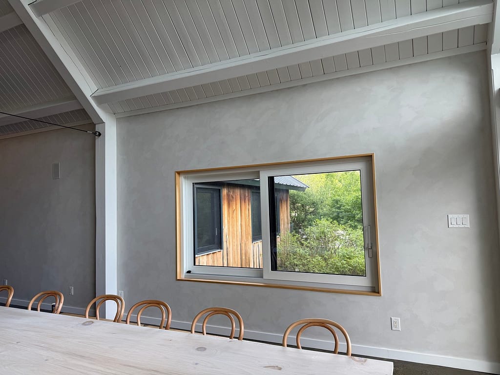 Grey lime wash dining-room wall framing a garden window in an Ottawa home
