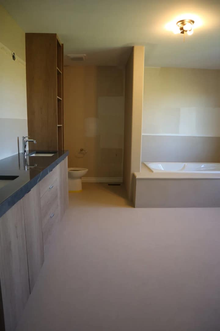 Bathroom floor tile covered in microcement with no grout lines and a new wood vanity