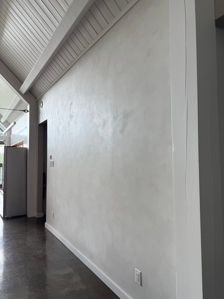 Hand-applied white lime wash wall along a vaulted hallway in an Ottawa home