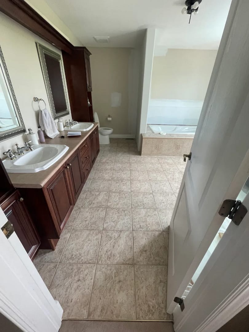 Long ensuite with speckled ceramic floor tile and grout lines before microcement